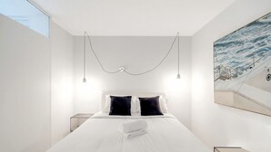 A modern hotel room with a large bed, two bedside tables, and a painting of a staircase on the wall. - The Little Bondi Base (Bondi Junction)