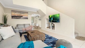 A modern living room with a sofa, coffee table, and TV mounted on the wall.