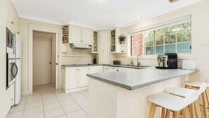 A modern kitchen with white cabinetry, a granite countertop, and a large island with bar stools.