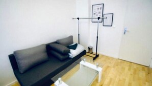 A room with a dark-colored sofa, a small table, a standing lamp, and a framed picture on the wall. - 3B Bedroom Apt, Up to 9P ; Only 10 Min to Augarten (Vienna)