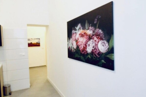 A hallway with a white wall and a painting of flowers.
