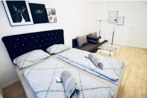 A room with a bed, a bedside table, a lamp, and wall art.