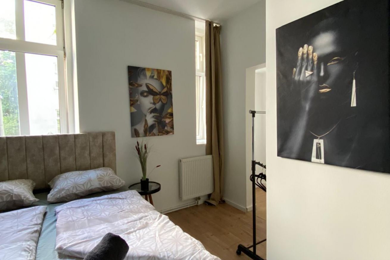 Ein Schlafzimmer mit Bett, Heizkörper, Fenster und einem Bild an der Wand.