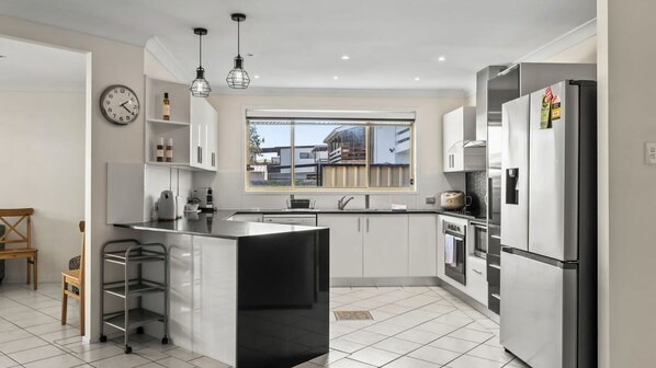 A modern kitchen with a central island, stainless steel appliances, and a window view.