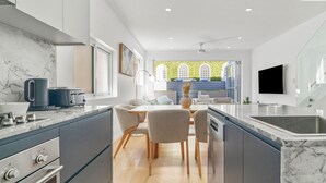 Una cocina moderna con una isla central, electrodomésticos integrados y un comedor con vistas a un jardín.