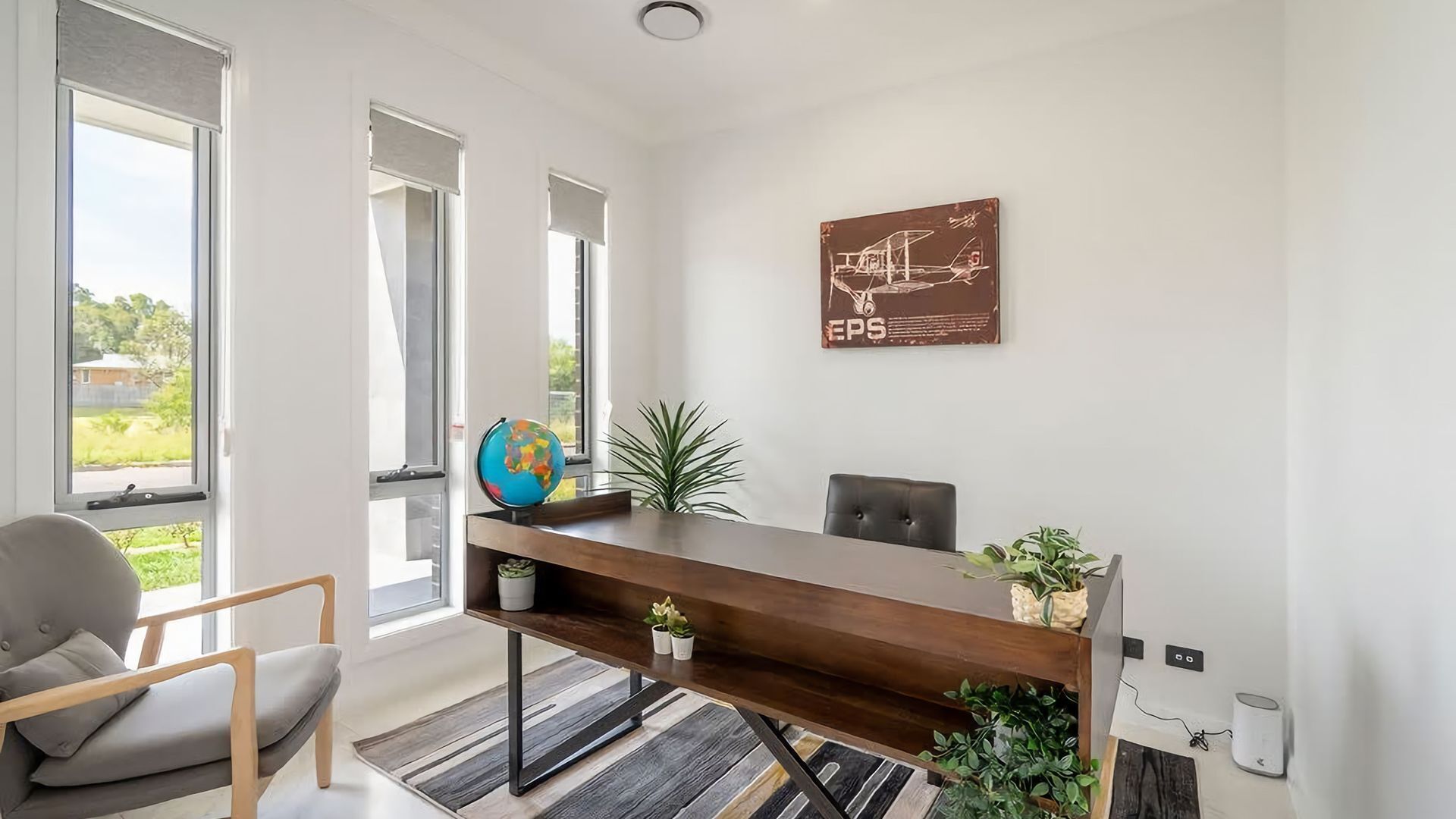 A modern office space with a wooden desk, a globe, and a potted plant.