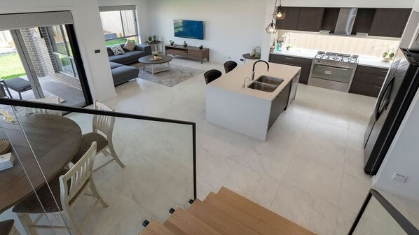 Un espacio habitable moderno y abierto con cocina, comedor y balcón.