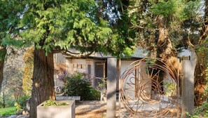 Experience the serene tranquility of this contemporary home surrounded by lush greenery and a striking metal sculpture.