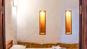 A room with a wooden ceiling, two wall-mounted lights, a bed with white bedding, and a wooden railing. - Hotel Tierra Roja  (Barichara)