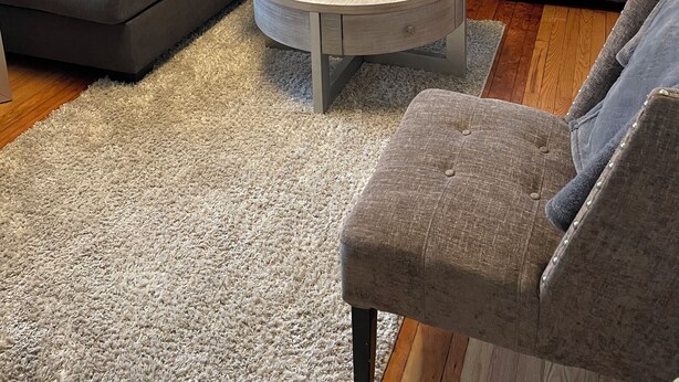 A living room with a sectional sofa, a round coffee table, and a gray armchair. - Modern Carriage house 2 blocks from Church Street (Burlington)