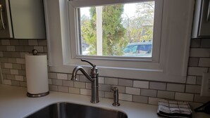 A kitchen with a stainless steel sink, a window above it, and a roll of paper towels on the counter. - Modern Carriage house 2 blocks from Church Street (Burlington)