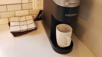 Ett kök med en Keurig-kaffemaskin, två koppar och en kökshandduk på bänken.