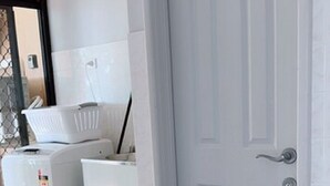 A room with a white door, a washing machine, and a dryer.