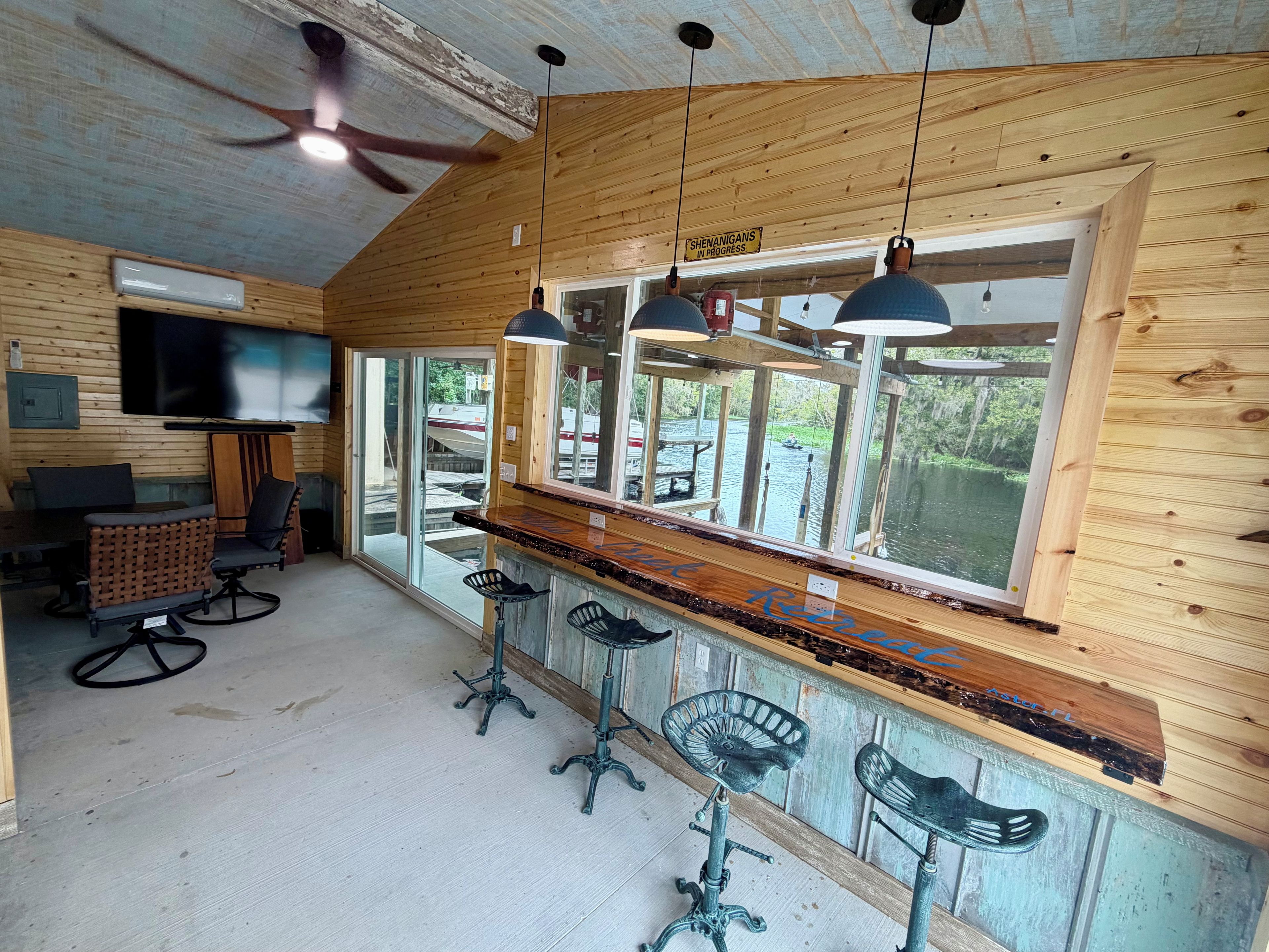 Een bar met houten wanden, een groot raam en een plafondventilator.