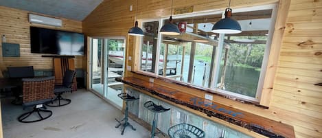 A bar area with wooden walls, a large window, and a ceiling fan.