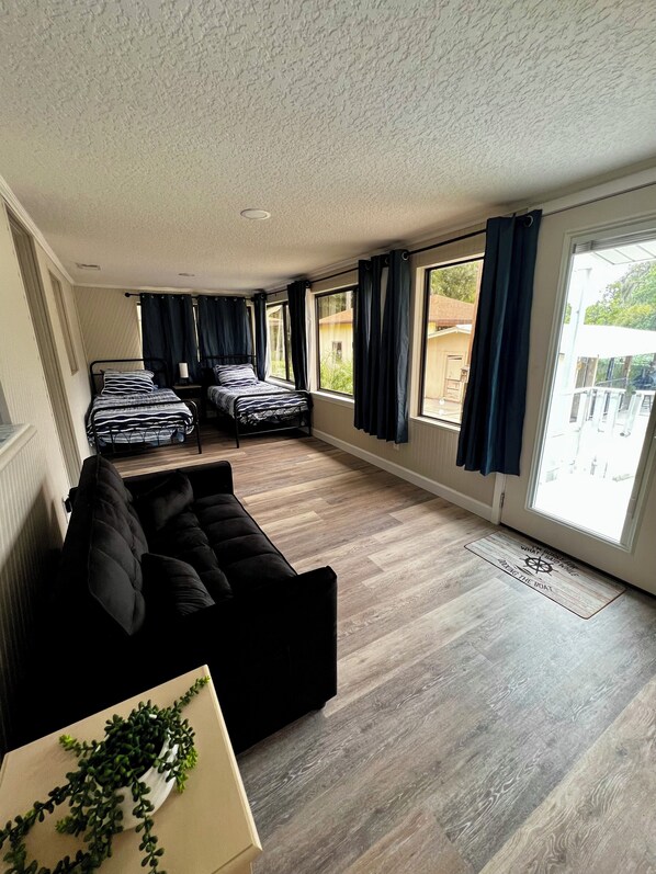 A compact room with a bed, a sofa, and a dining table.