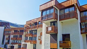 A multi-story hotel with wooden balconies and large windows. - Le Roc de Peclet by Interhome (Val Thorens)