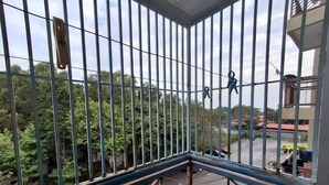 A balcony with metal railings, a view of a parking area, and trees in the background. - Homestay WaDi 2, Apartment with pool near beach (Port Dickson Town)