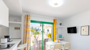 A modern hotel room with a dining area, a kitchen, and a view of the outside.