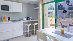 A modern kitchen with white cabinets, a microwave, and a dining area with a table and chairs.