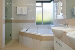 A modern bathroom with a glass shower enclosure, a large freestanding bathtub, and a dual sink vanity. - ACACIA WATERS (Taupo)