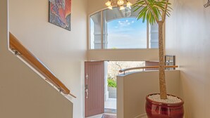 A staircase with a potted palm tree, a door, and a view of the outside. - ACACIA WATERS (Taupo)