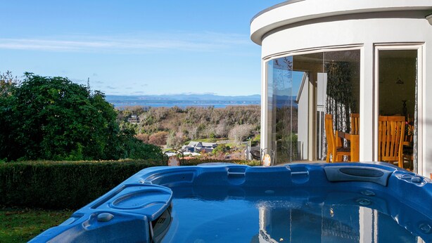 A hot tub with a clear view of a mountainous landscape and a residential area in the background. - ACACIA WATERS (Taupo)