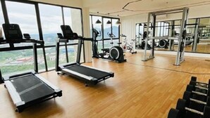 Ein großzügiger Fitnessraum mit Cardiogeräten, Krafttrainingsgeräten und einem großen Fenster mit Blick ins Freie.