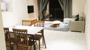 Ein modernes Wohnzimmer mit Essbereich, einem Flachbildfernseher, einem Kamin und einem großen Fenster mit Vorhängen.