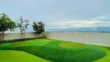 A well-maintained lawn with a circular pattern, a low wall, and a view of distant mountains.