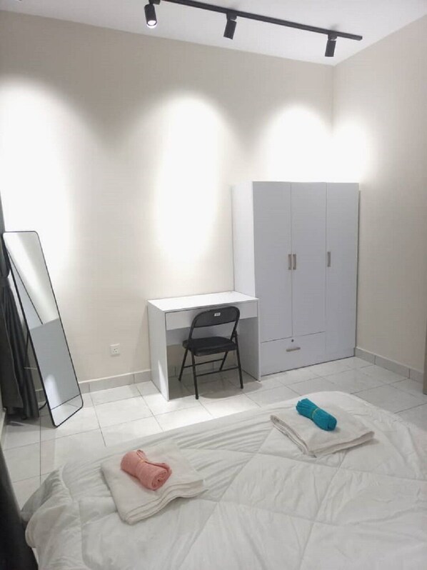Un dormitorio con cama, escritorio, silla, armario y espejo.