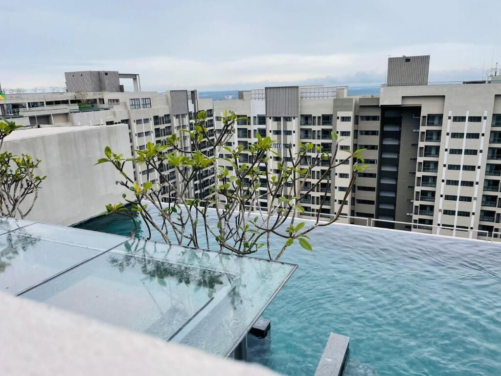 Una piscina en la azotea con agua azul cristalina, rodeada de edificios modernos.