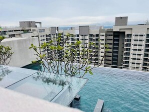 Una piscina en la azotea con agua azul cristalina, rodeada de edificios modernos.