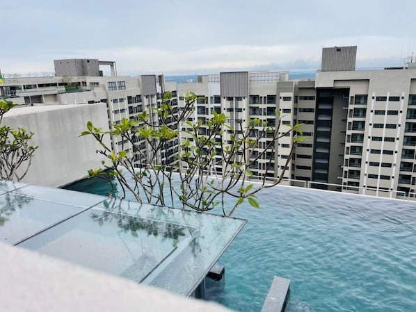 Una piscina en la azotea con agua azul cristalina, rodeada de edificios modernos.