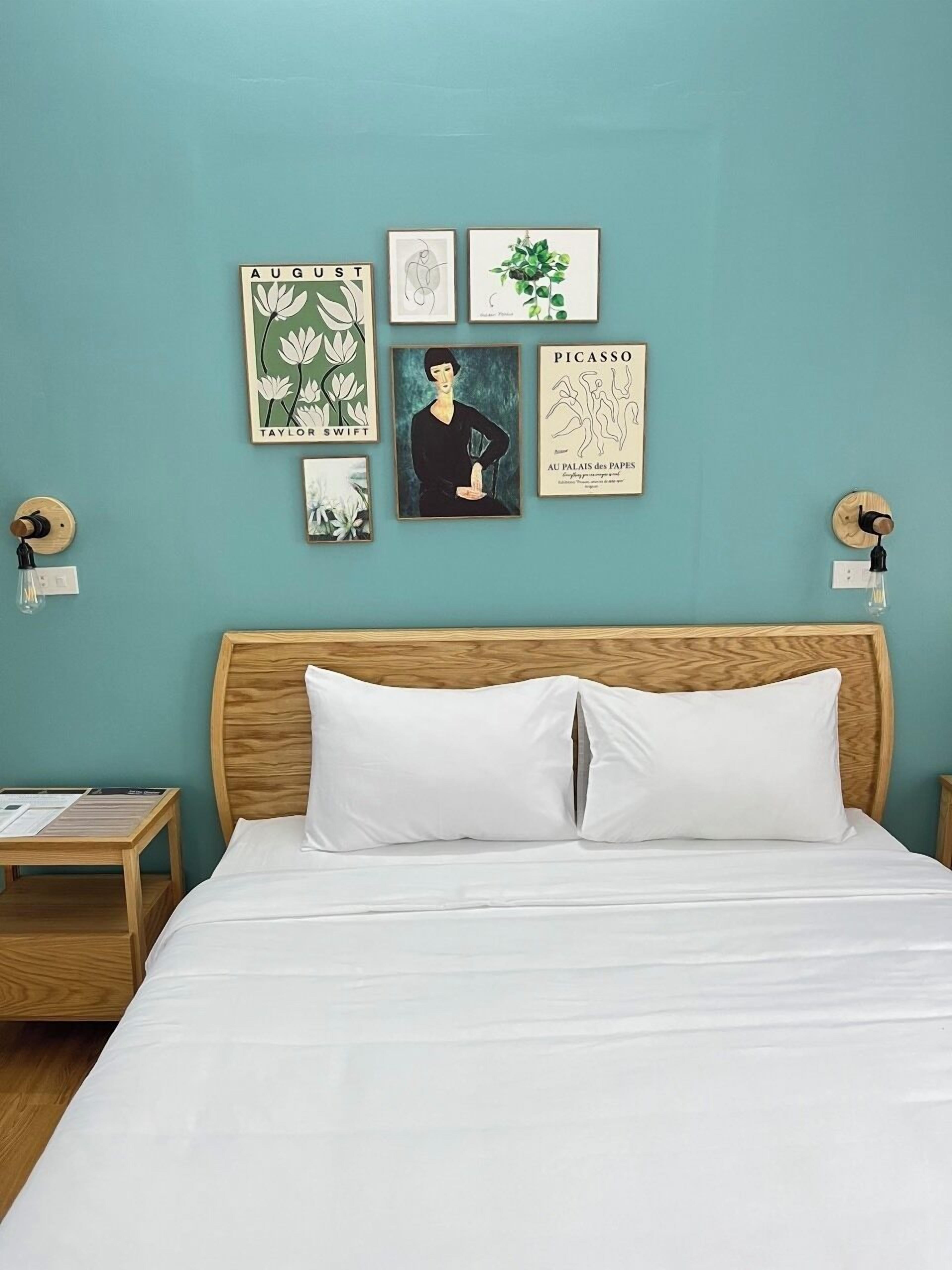 A bedroom with a bed, a nightstand, and a wall with framed artwork.