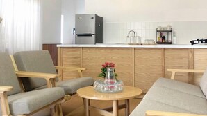 A modern living room with two grey sofas, a wooden coffee table, and a kitchen area with a refrigerator and white cabinets. - Hidden Hue Homestay (Hue)