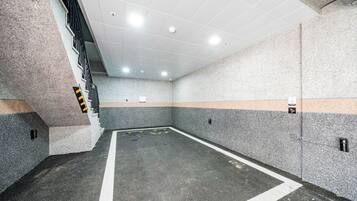 Un estacionamiento con piso de concreto, paredes blancas y una escalera a la izquierda.