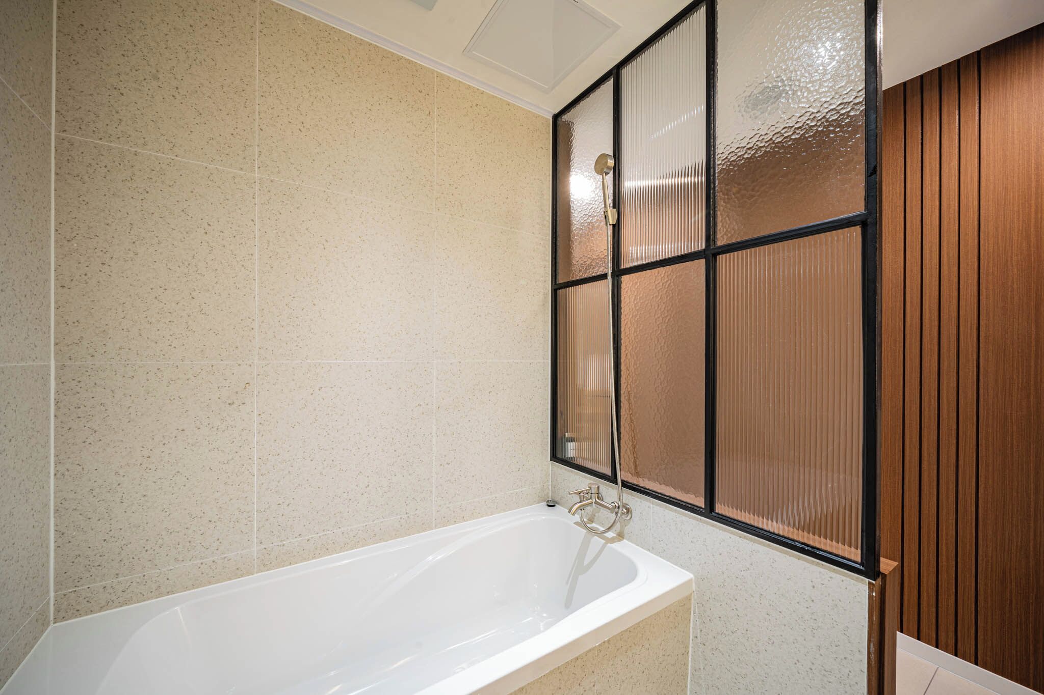 Une salle de bain moderne avec une baignoire sur pieds, une cloison en verre dépoli et un lambris en bois.