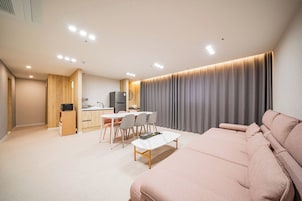 Una sala de estar moderna con un sofá, un comedor con sillas y una mesa, y una cocina equipada.