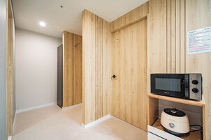 Cocina compacta con paneles de madera, microondas y cocedor de arroz.