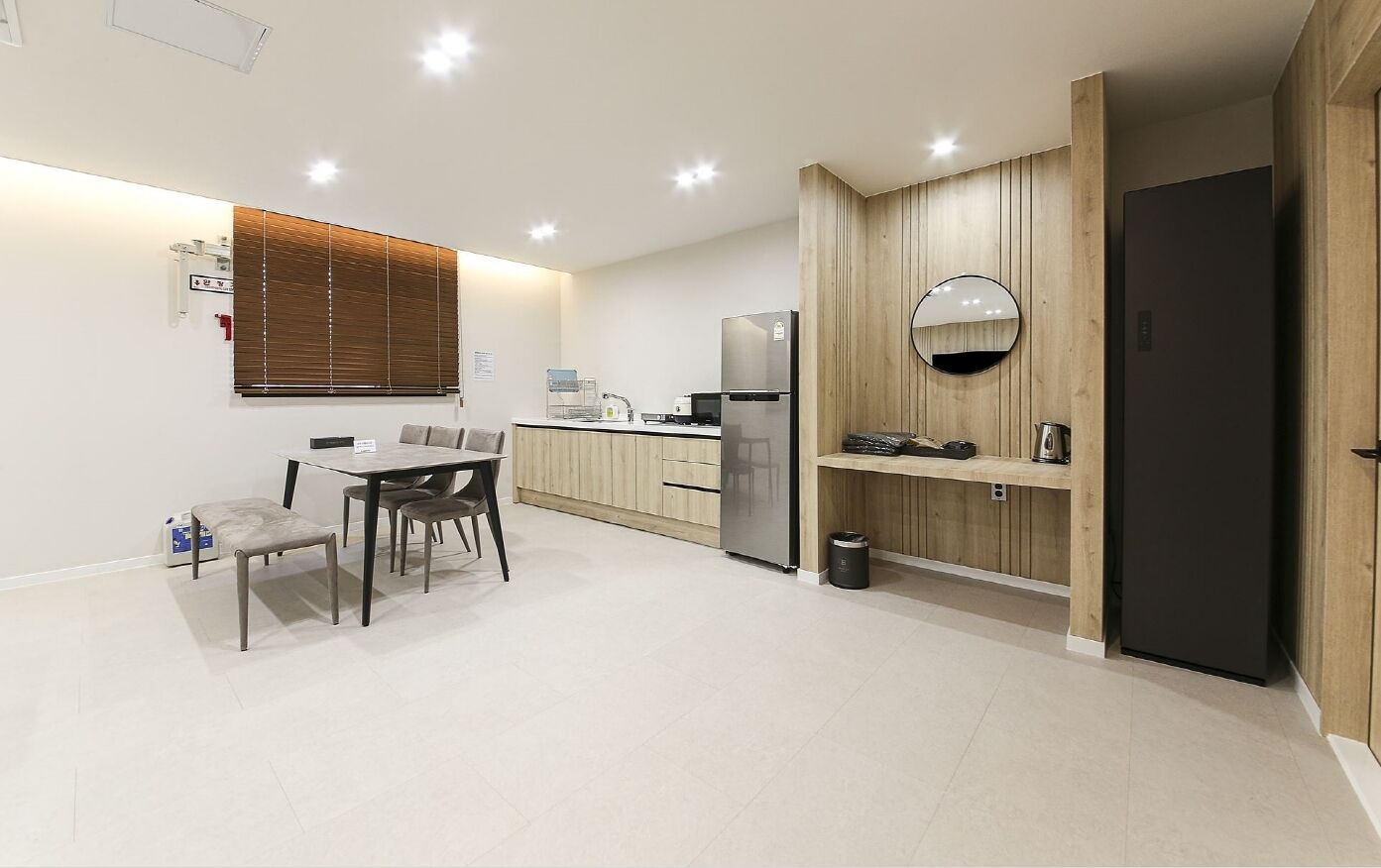 Una cocina moderna con comedor, paneles de madera, refrigerador y cafetera.