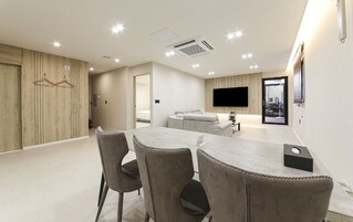 Habitación de hotel moderna con comedor, televisor de pantalla plana y pared de paneles de madera.