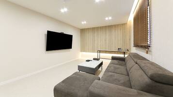 Una sala de estar moderna con un sofá seccional, un televisor de pantalla plana montado en la pared, una mesa de centro y un mueble empotrado para la televisión.