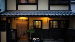 A traditional Japanese building with a wooden door, potted plants, and a tiled roof. - Kokonoe Machiya (Kyoto)
