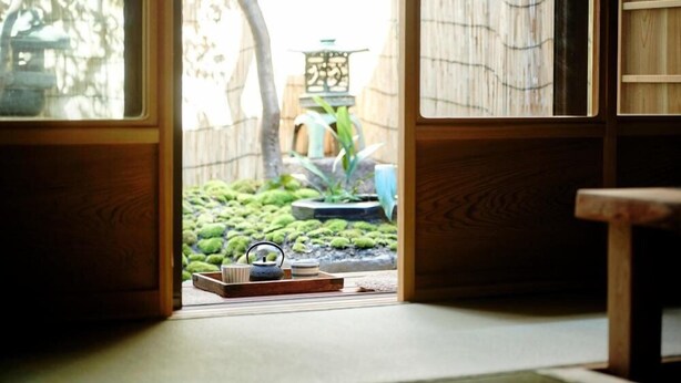 A traditional Japanese room with tatami flooring, a shoji screen door, and a small garden area visible through the door. - Kokonoe Machiya (Kyoto)