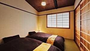 A traditional Japanese room with tatami flooring, a shoji screen, and a futon bed. - Kokonoe Machiya (Kyoto)