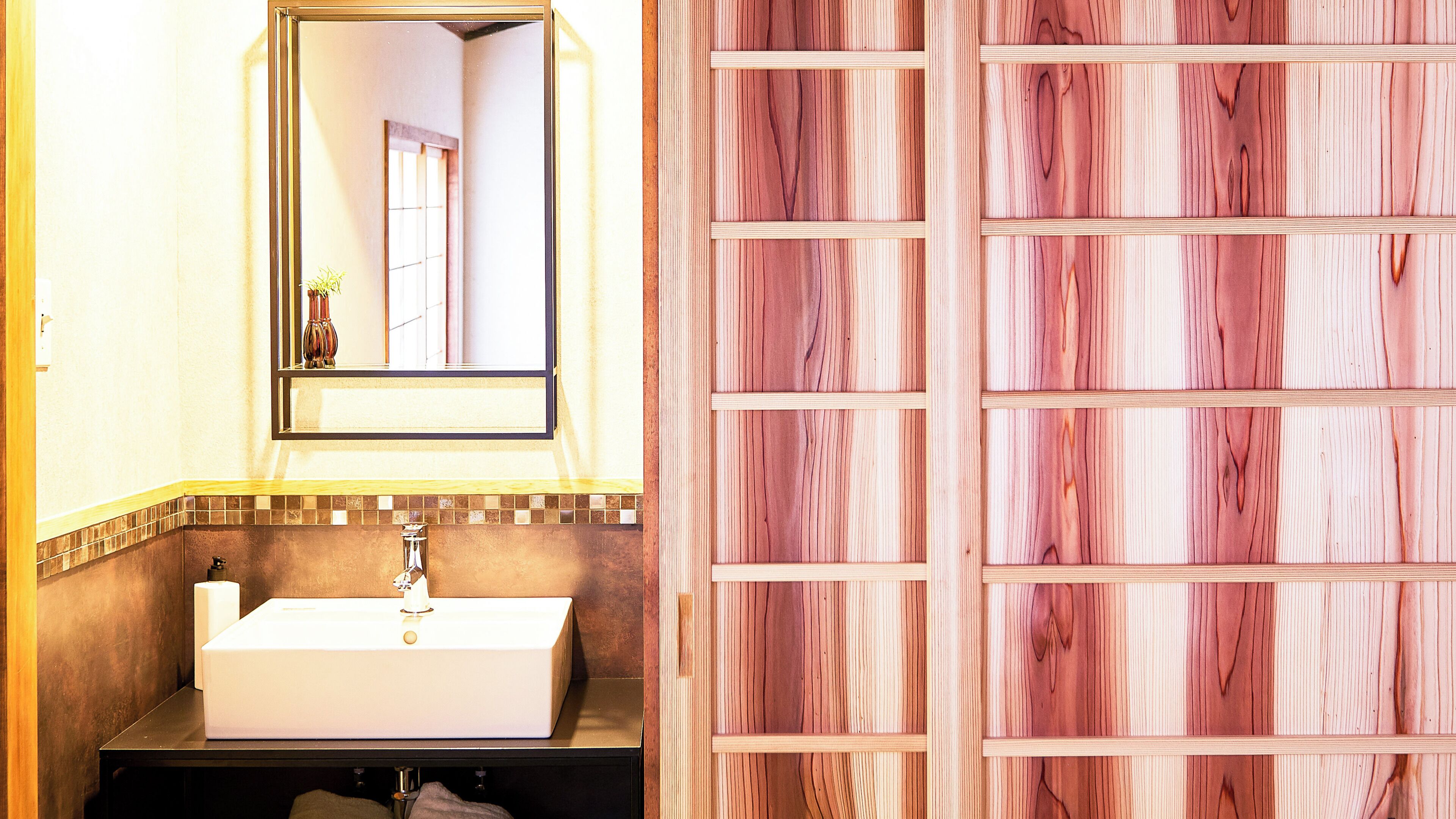 A bathroom with a white sink, a mirror, and a wooden panel wall.