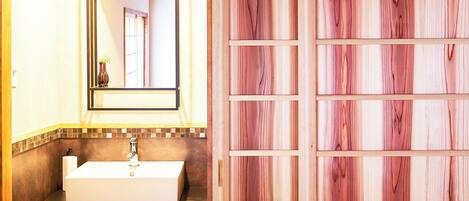 A bathroom with a white sink, a mirror, and a wooden panel wall.