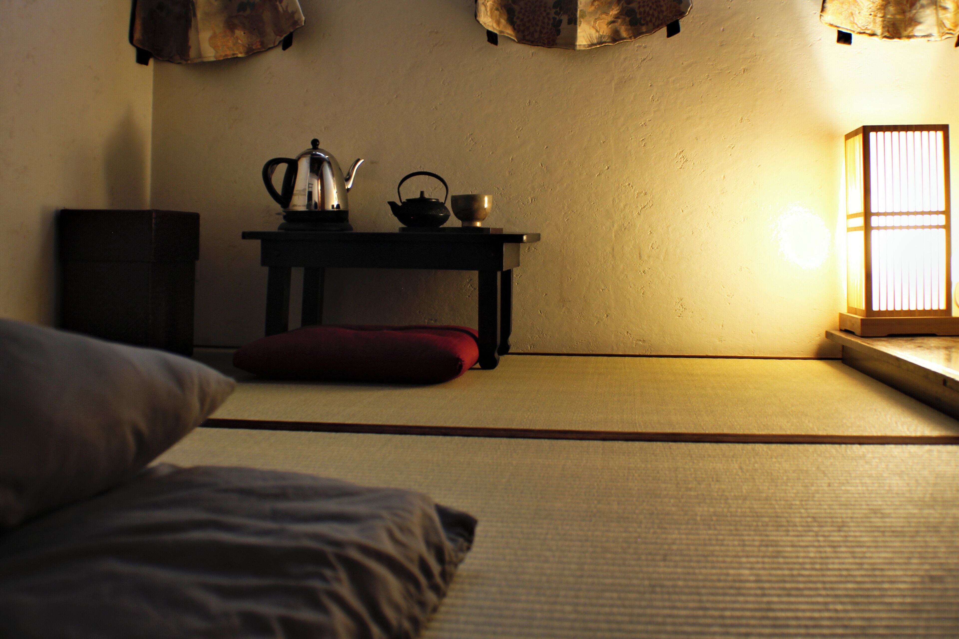 Una habitación japonesa tradicional con suelo de tatami, una mesa baja con un hervidor y una tetera, y un biombos shoji.