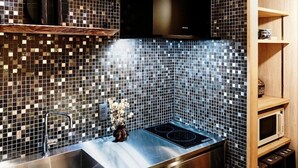 A kitchen with a tiled backsplash, stainless steel sink, and a built-in microwave. - Kokonoe Machiya (Kyoto)